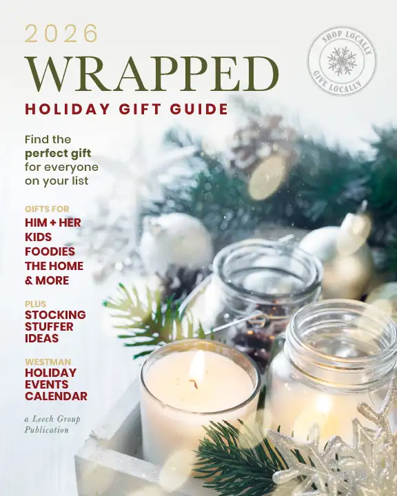 Mockup of Wrapped Guide 2026 cover showing a set of three candles in glass containers in the foreground, with pine and winter greens in the background. The candles are lit. The text reads "Find the perfect gift for everyone on your list. Gifts for him, her, kids, foodies, the home, and more. Plus stocking stuffer ideas. Westman Holiday Events Calendar. A publication of Leech Group"